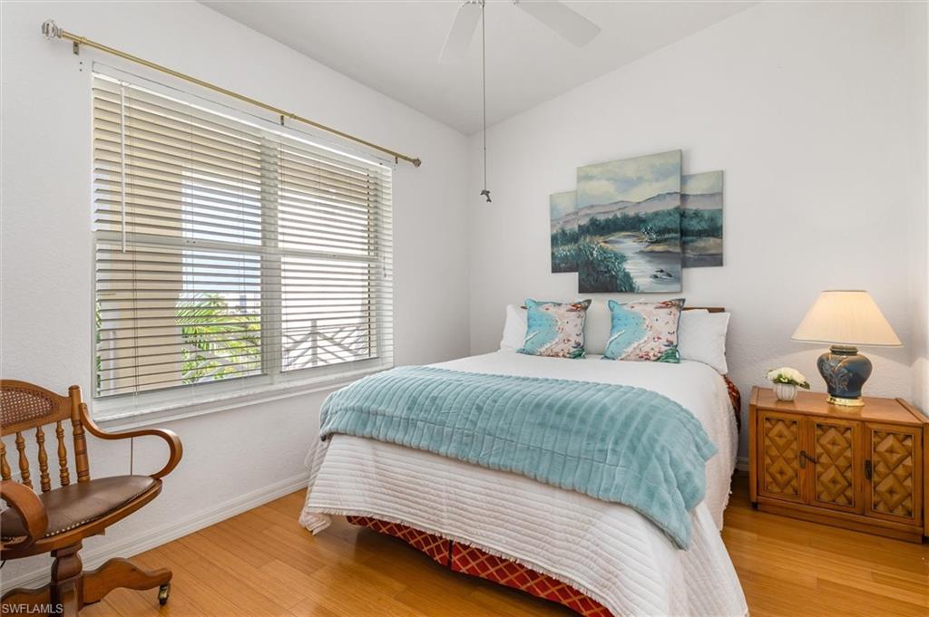 Guest bedroom with wood floors, ceiling fan, walk-in closet and lofted ceiling