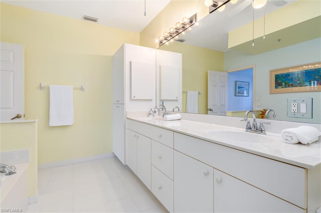 Primary ensuite bathroom with dual vanity, garden tub, walk-in shower and linen closet. Ceramic tile floor.