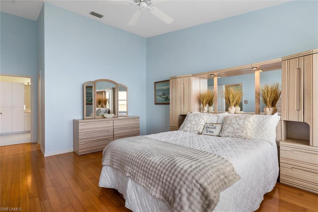 Primary bedroom featuring wood flooring, multiple windows, ceiling fan, vaulted ceiling, and vast water views
