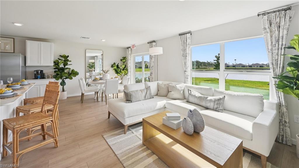 Model Home. Open concept living area featuring light-toned flooring, large windows with views of a body of water, and recessed lighting