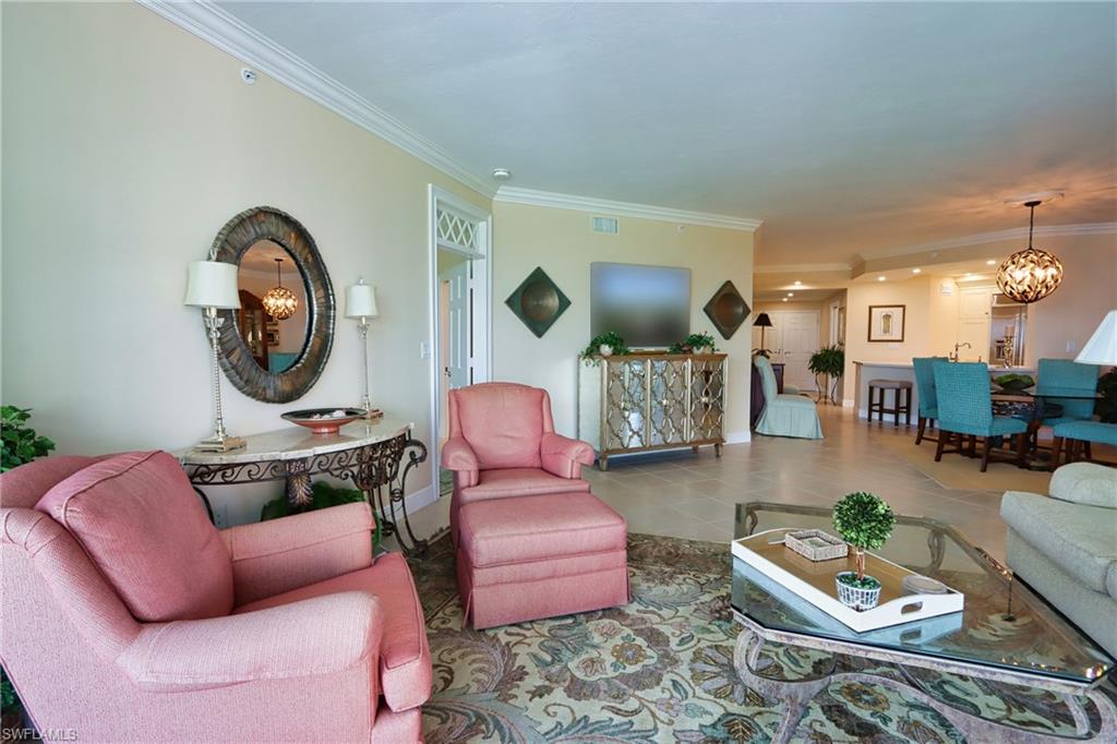 Tiled living room featuring crown molding and an inviting chandelier