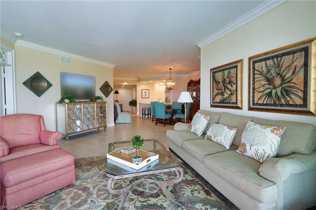 Tiled living room with ornamental molding and an inviting chandelier