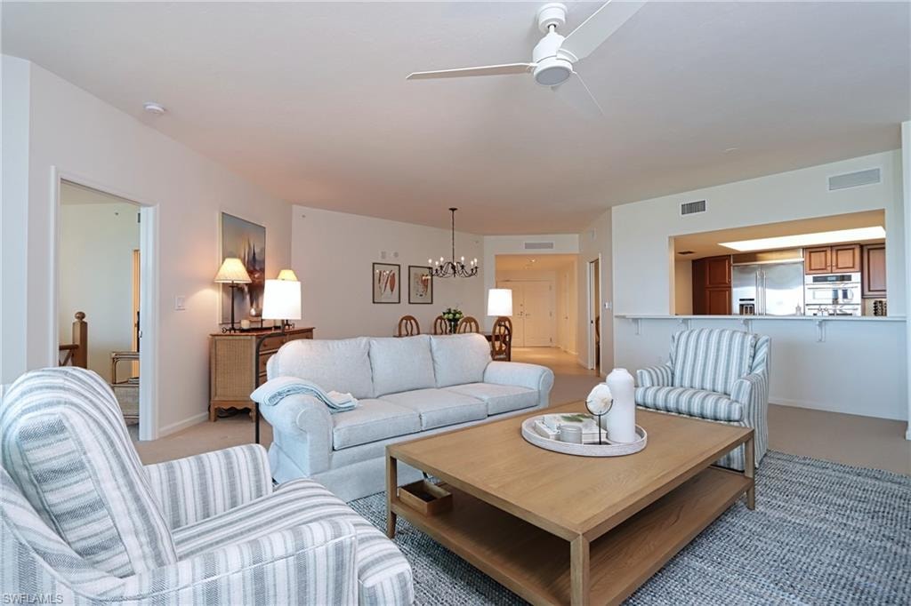 Living room featuring carpet flooring and ceiling fan with notable chandelier