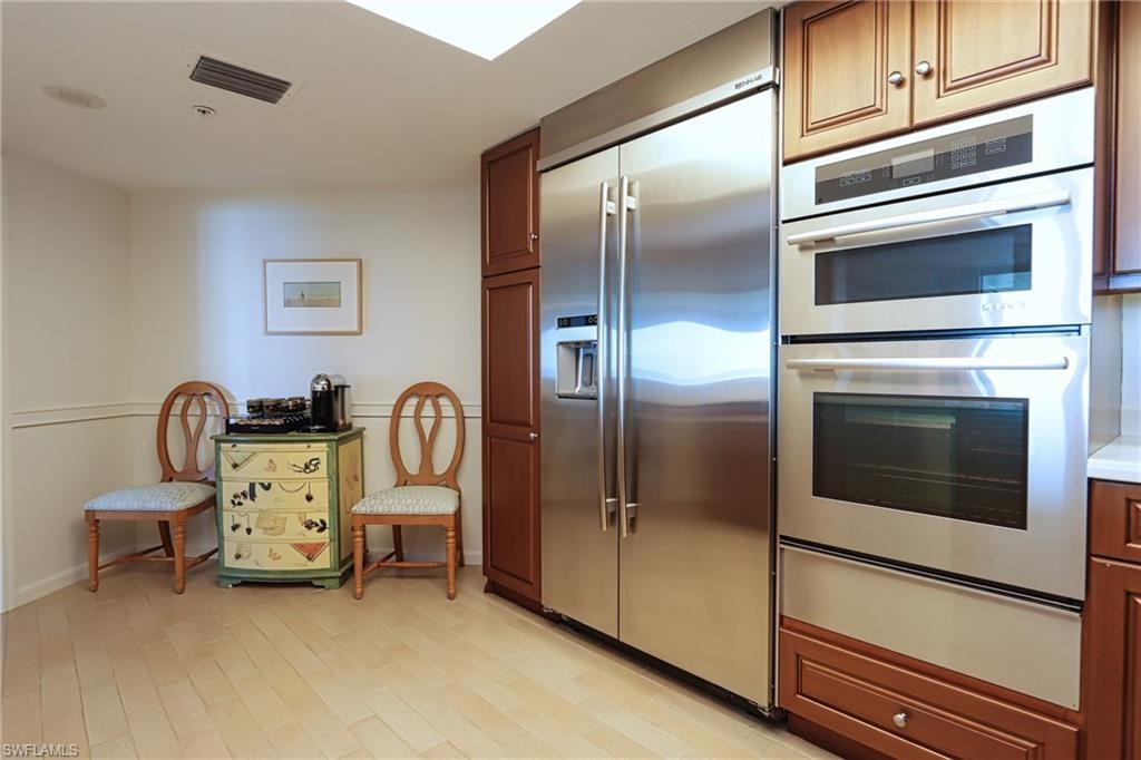 Kitchen with appliances with stainless steel finishes and light hardwood / wood-style flooring