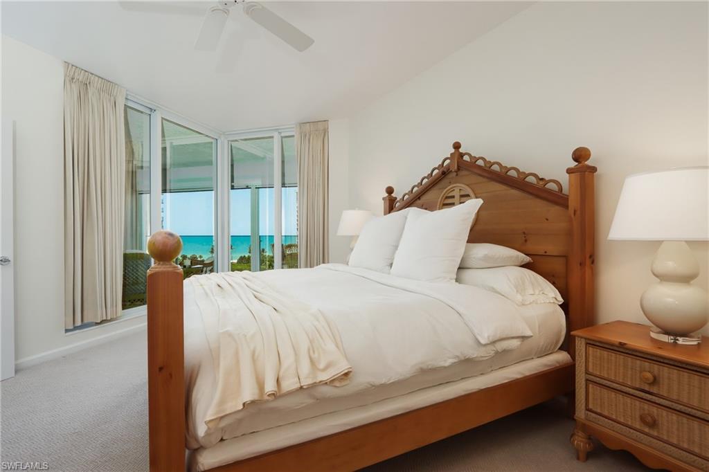 Carpeted bedroom featuring ceiling fan, a water view, and access to exterior