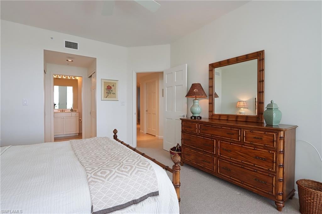 Bedroom with ceiling fan, connected bathroom, and light colored carpet