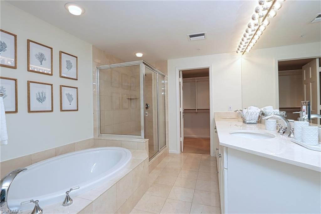 Bathroom featuring shower with separate bathtub, tile flooring, and double sink vanity