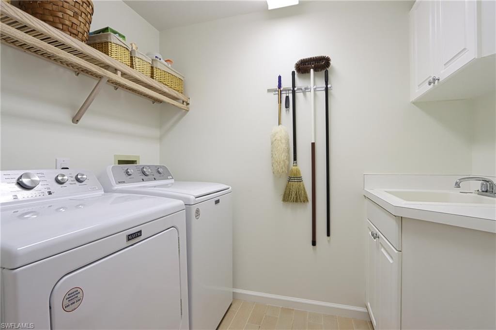 Washroom featuring cabinets, sink, independent washer and dryer, and light tile flooring