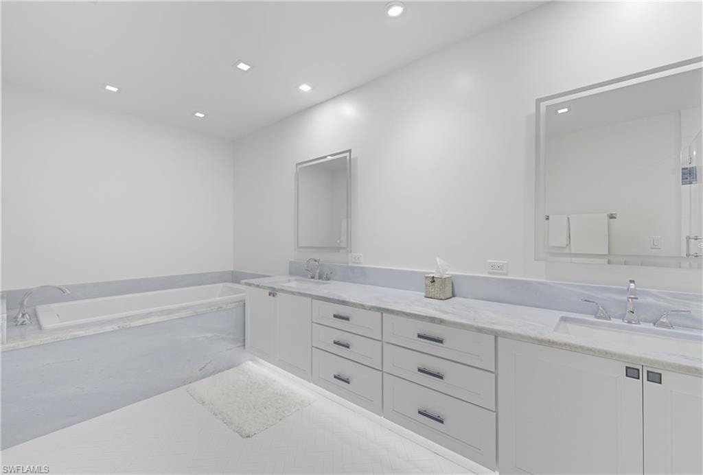 Bathroom with double vanity, a bath, and recessed lighting