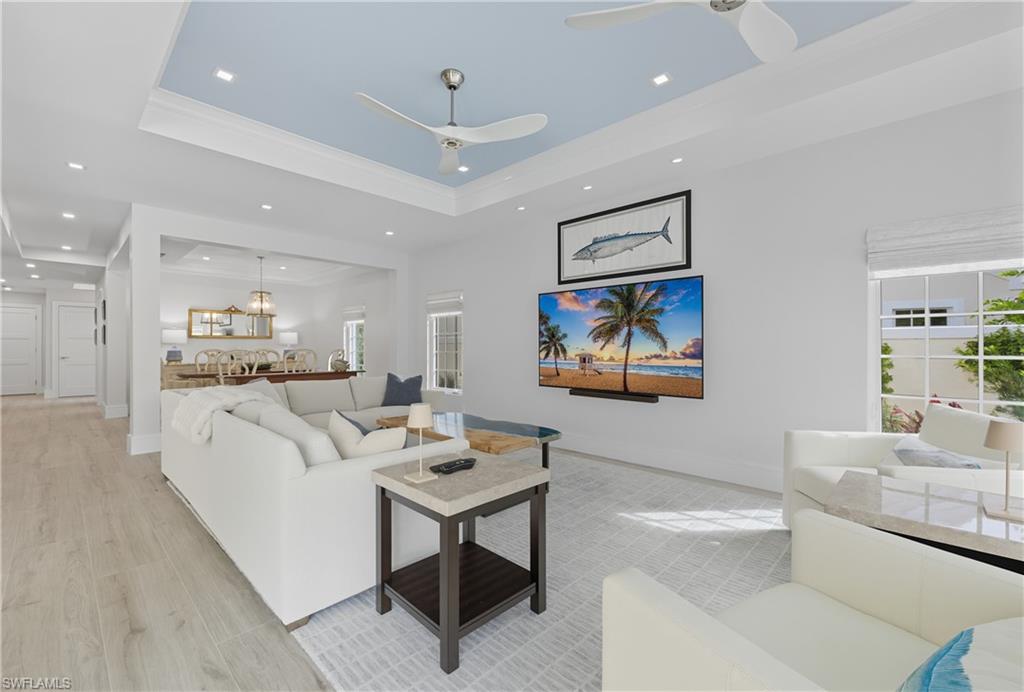 Living area featuring a raised ceiling, recessed lighting, and wood finished floors