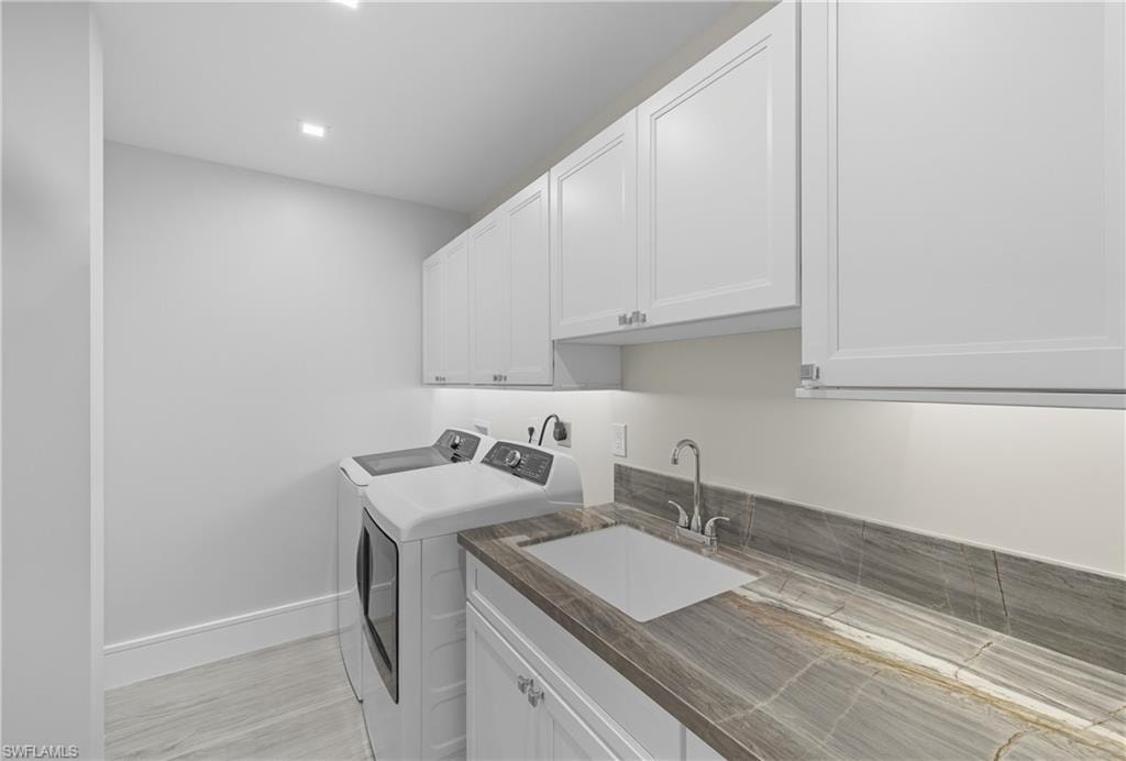 Washroom with cabinet space, washer and dryer, and light wood-type flooring
