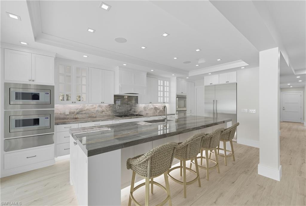 Kitchen with a tray ceiling, white cabinetry, a breakfast bar area, backsplash, and recessed lighting
