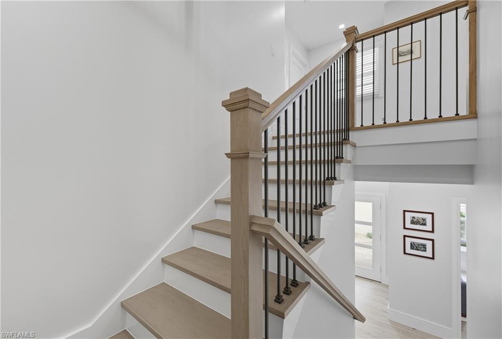 Stairway with wood finished floors and a towering ceiling