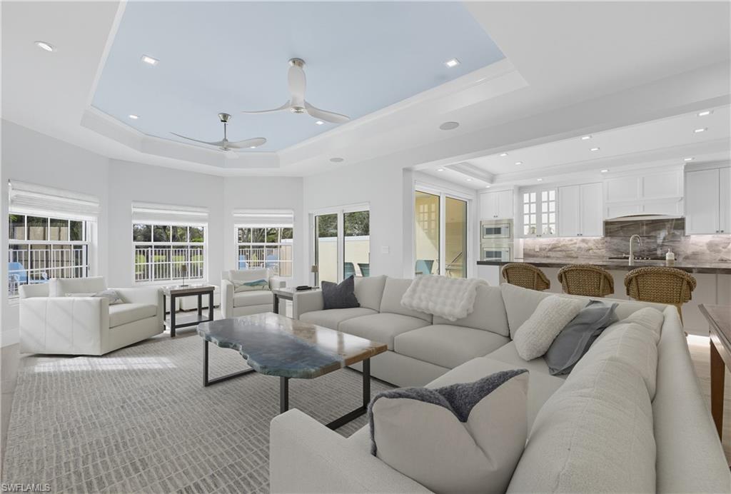 Living room with a tray ceiling, recessed lighting, and a ceiling fan