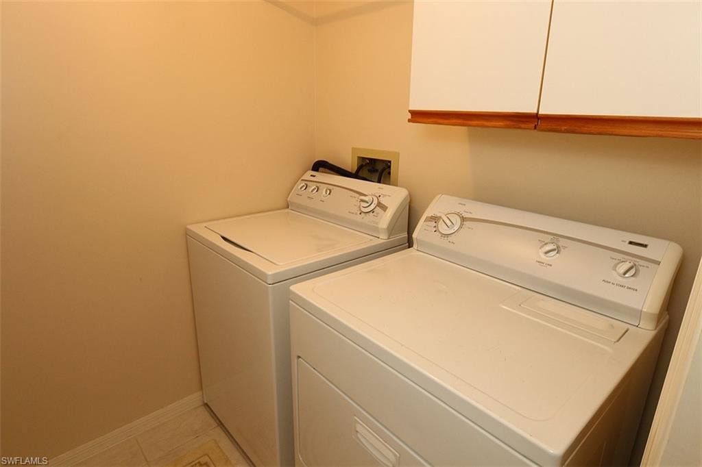 Laundry room featuring cabinets, washer hookup, light tile floors, and washing machine and clothes dryer