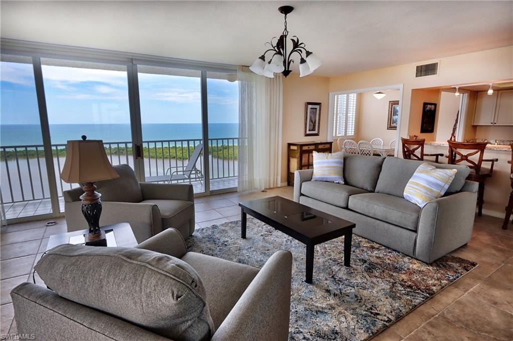 Tiled living room featuring a water view and an inviting chandelier