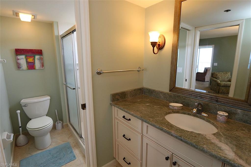 Bathroom with a shower with door, tile flooring, large vanity, and toilet