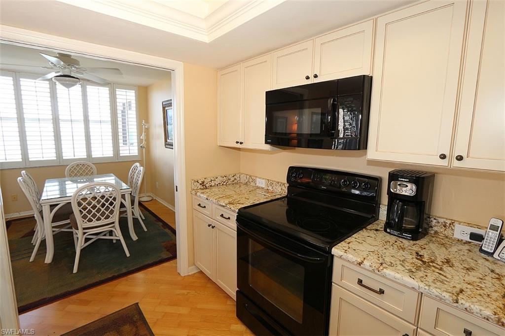 Kitchen with ornamental molding, light hardwood / wood-style flooring, black appliances, white cabinets, and ceiling fan
