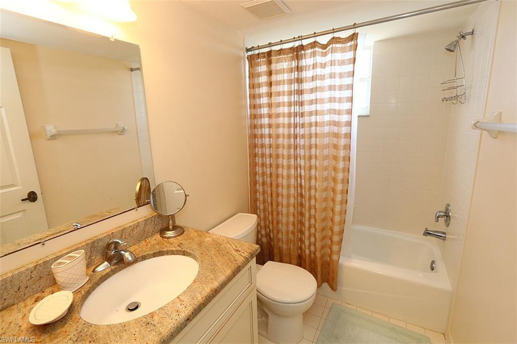 Full bathroom with tile floors, shower / bath combination with curtain, toilet, and vanity