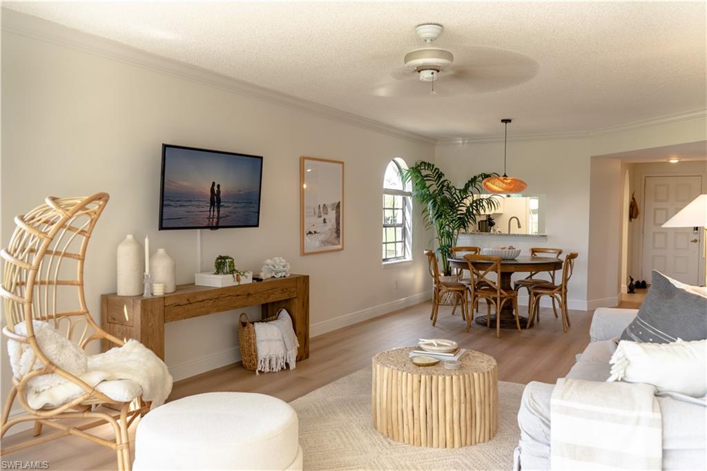 Living area with light wood-type flooring, ceiling fan, baseboards, and ornamental molding