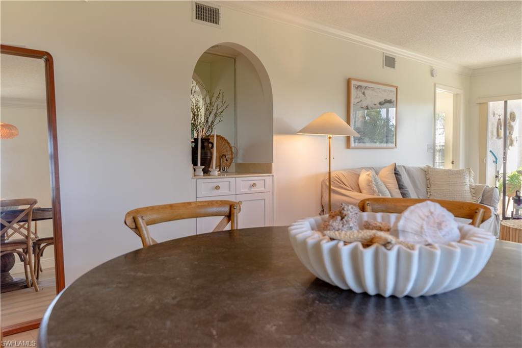 Dining room featuring crown molding, visible vents, and a textured ceiling