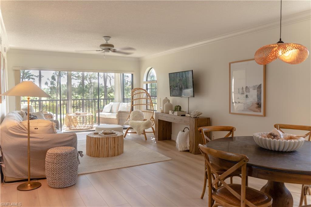 Living room featuring light wood-style floors, ornamental molding, and ceiling fan