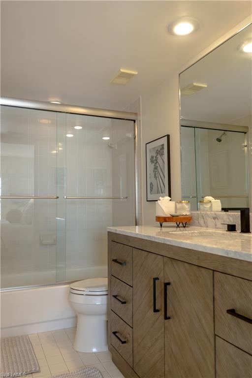 Bathroom with visible vents, bath / shower combo with glass door, toilet, vanity, and tile patterned floors