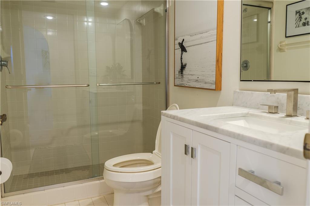 Full bath with toilet, a stall shower, and vanity