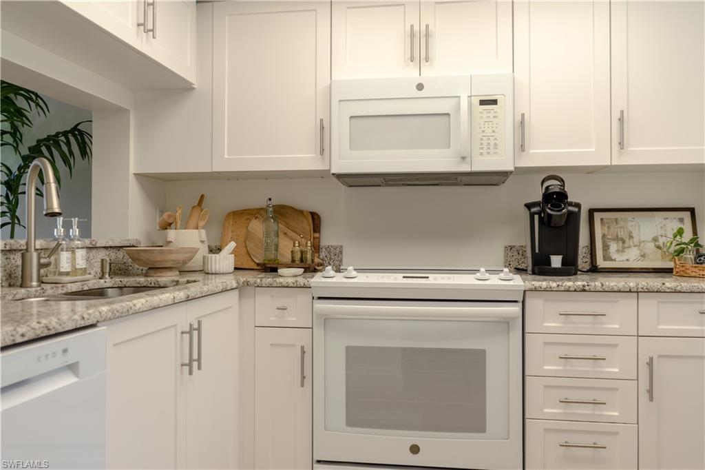 Kitchen featuring a sink, white cabinetry, and white appliances
