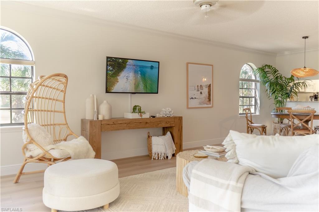 Living area featuring light wood-style flooring, baseboards, crown molding, and ceiling fan