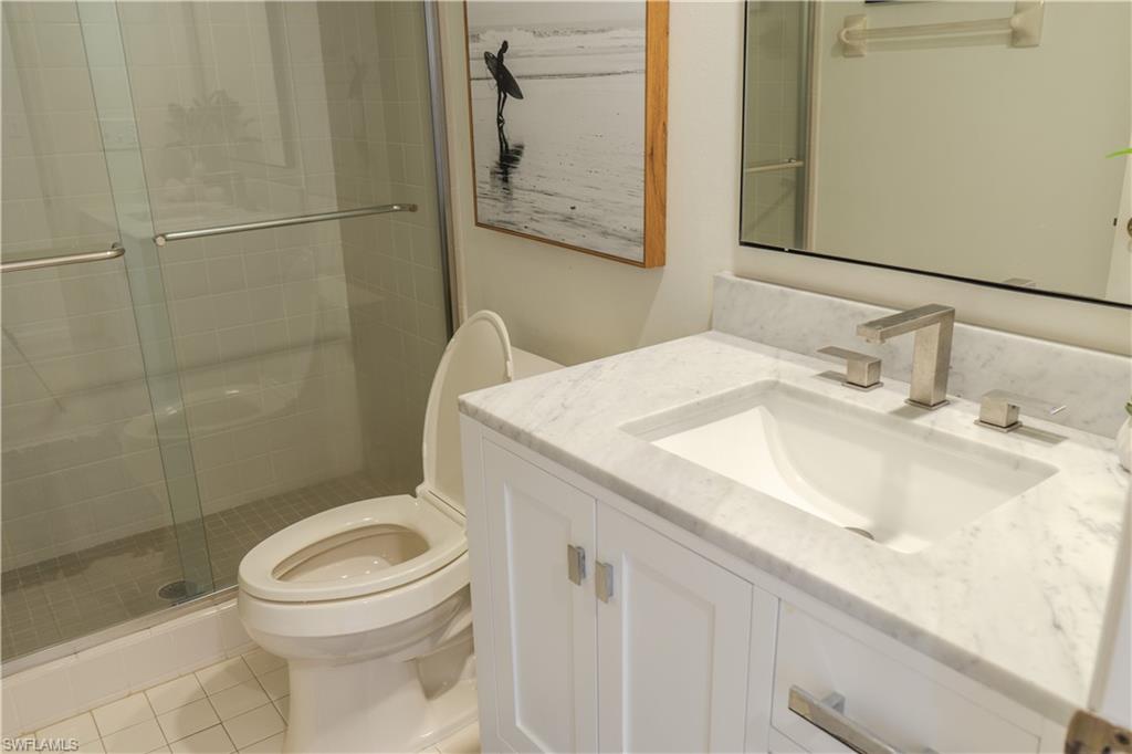 Bathroom with toilet, a shower stall, tile patterned flooring, and vanity