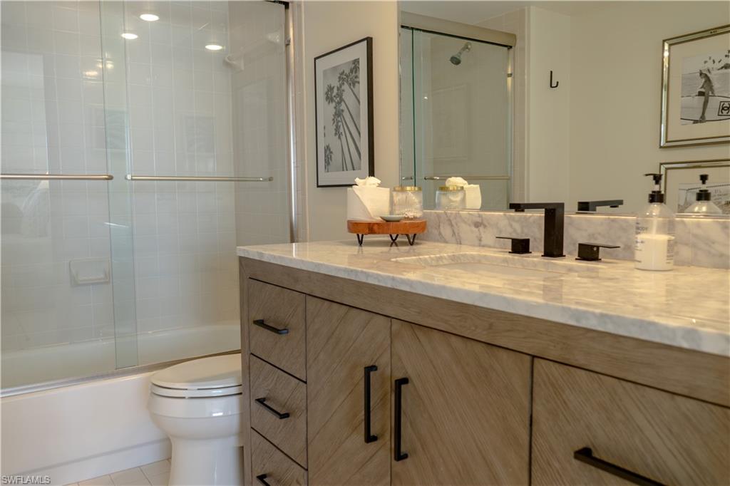 Full bath featuring tile patterned flooring, toilet, vanity, and enclosed tub / shower combo