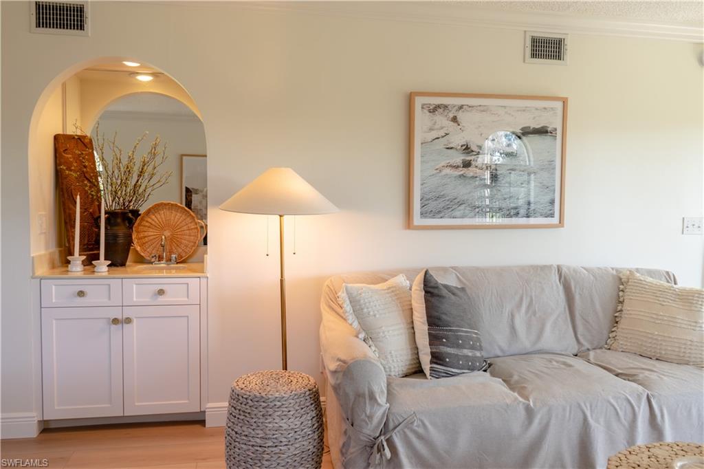 Living room featuring light wood finished floors, visible vents, and crown molding
