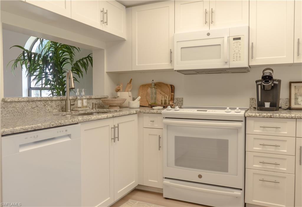 Kitchen featuring white cabinets, a sink, white appliances, light wood-style floors, and light stone countertops