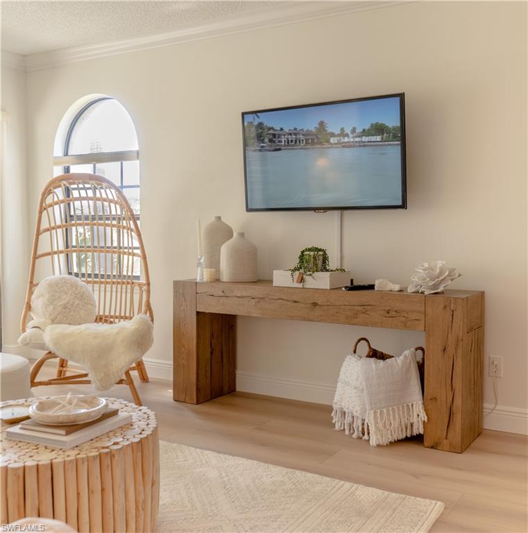 Living area with ornamental molding, wood finished floors, and a textured ceiling