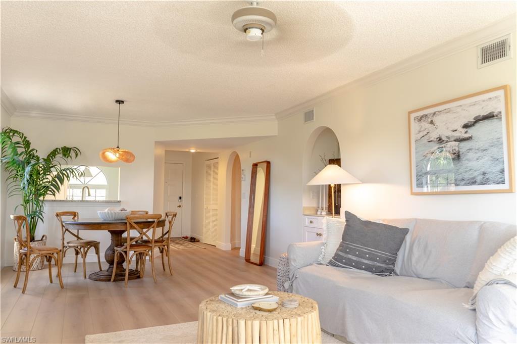 Living area featuring light wood-style floors, arched walkways, visible vents, and a textured ceiling