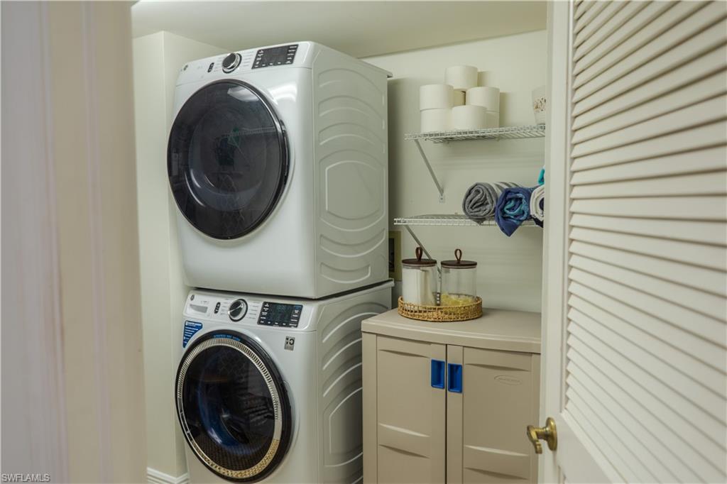 Dedicated laundry area featuring a stacked washer and dryer, wire shelving, and a louvered door