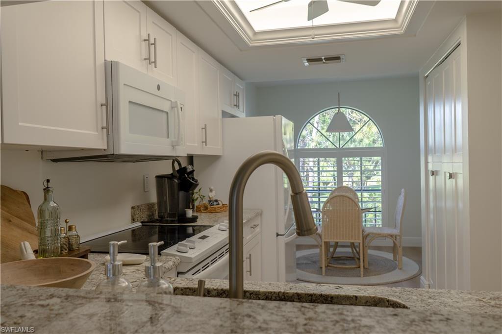 The kitchen features white cabinetry, granite countertops, and a modern microwave