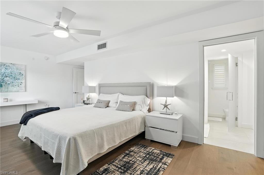 Bedroom with wood finished floors, ceiling fan, and ensuite bathroom