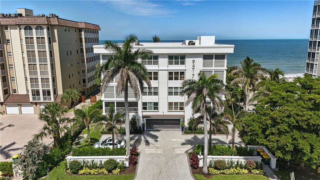 View of property with decorative driveway, a water view, and an attached garage