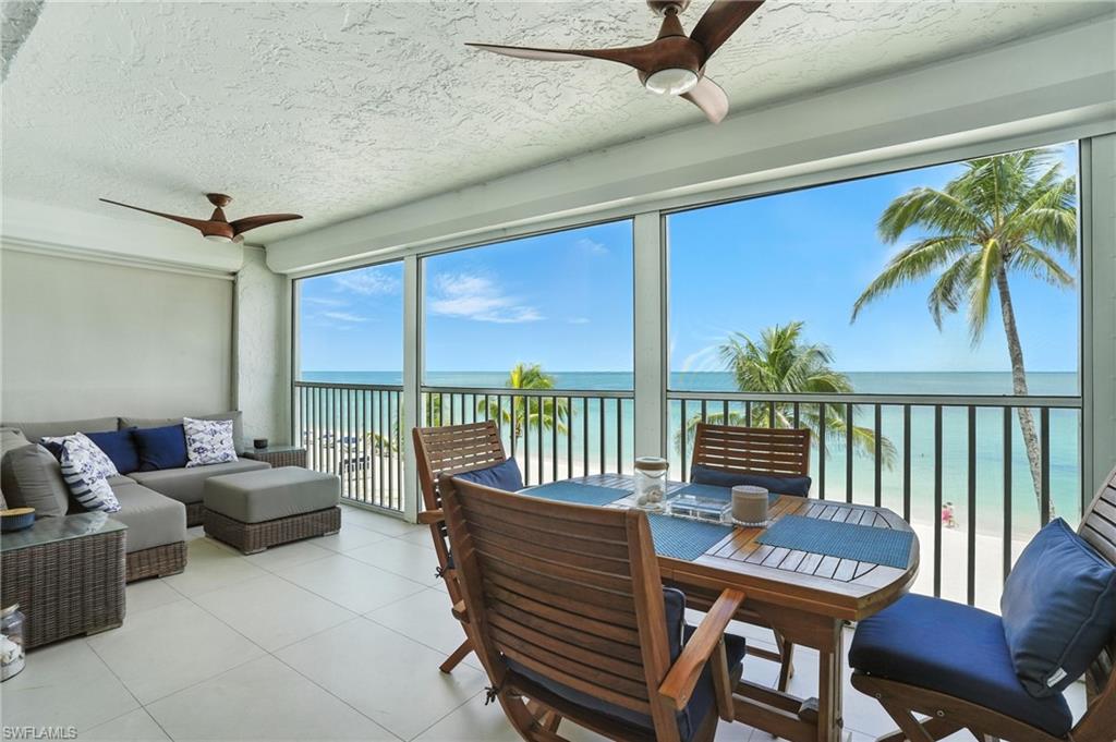 Sunroom / solarium with view of water and beach, a textured ceiling, and tile patterned floors