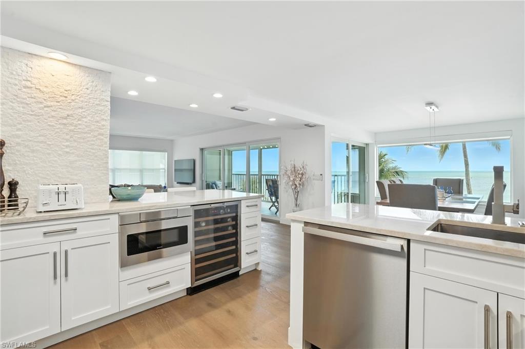 Kitchen with wine cooler, stainless steel appliances, recessed lighting, light countertops, and light wood-style floors
