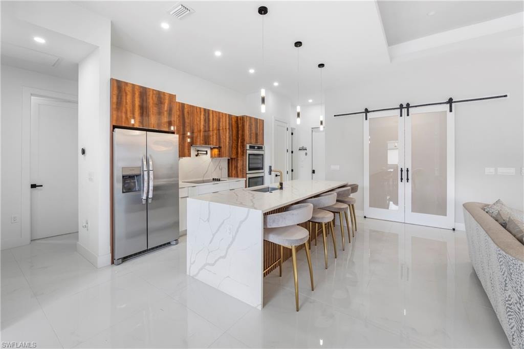 Modern kitchen featuring a waterfall island with a built-in sink and pendant lighting