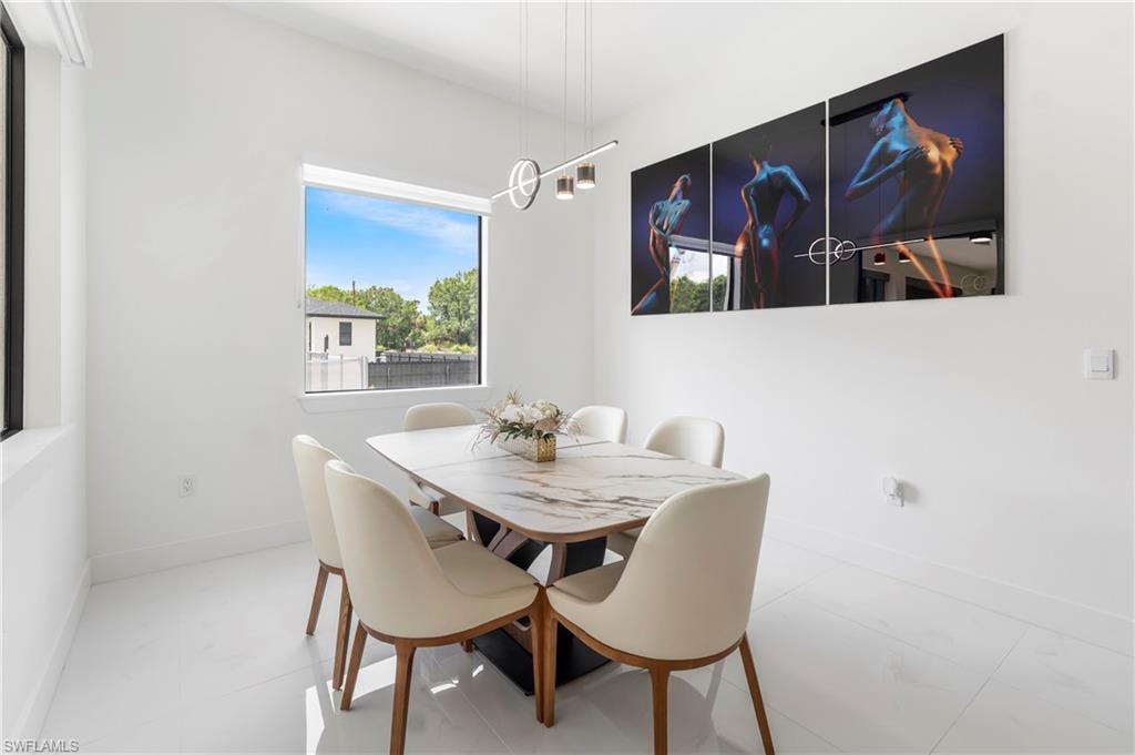 Dining area featuring white walls, large windows, and contemporary pendant lighting