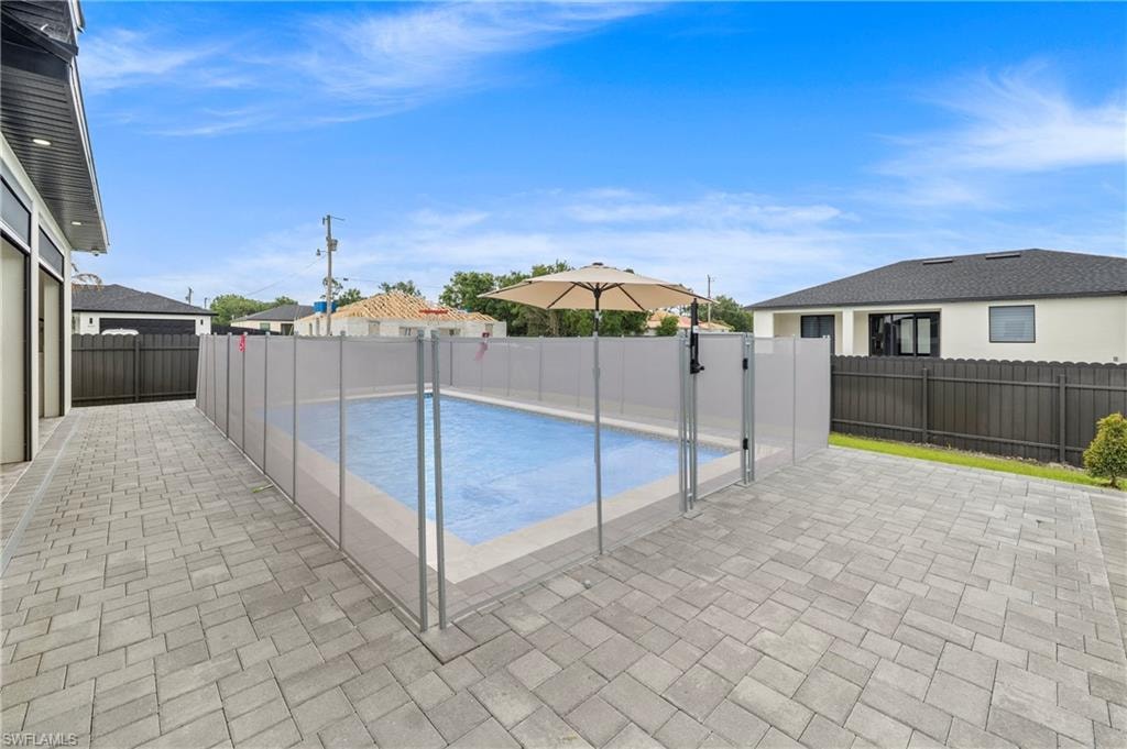 Outdoor living space featuring a blue-tiled swimming pool with a safety fence