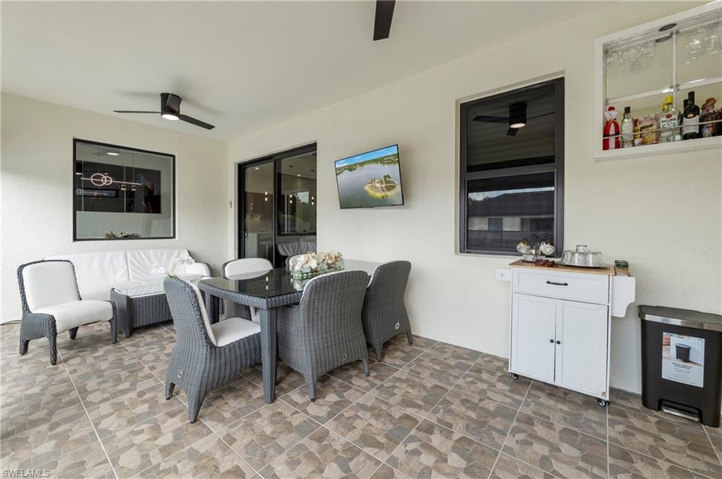 Covered patio featuring tiled flooring, black frame windows, and ceiling-mounted fans