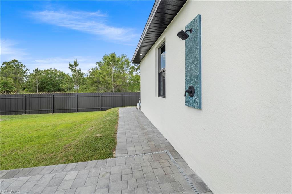 Exterior wall featuring an outdoor shower with dark bronze fixtures set against a decorative panel