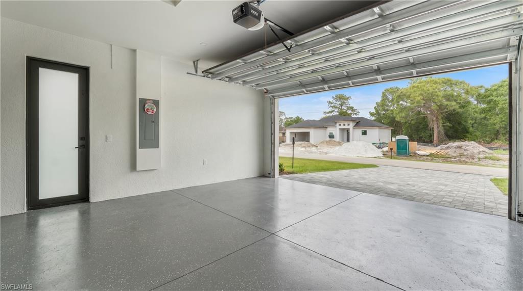 Spacious garage featuring epoxy flooring, a modern frosted glass door, and a full-view garage door