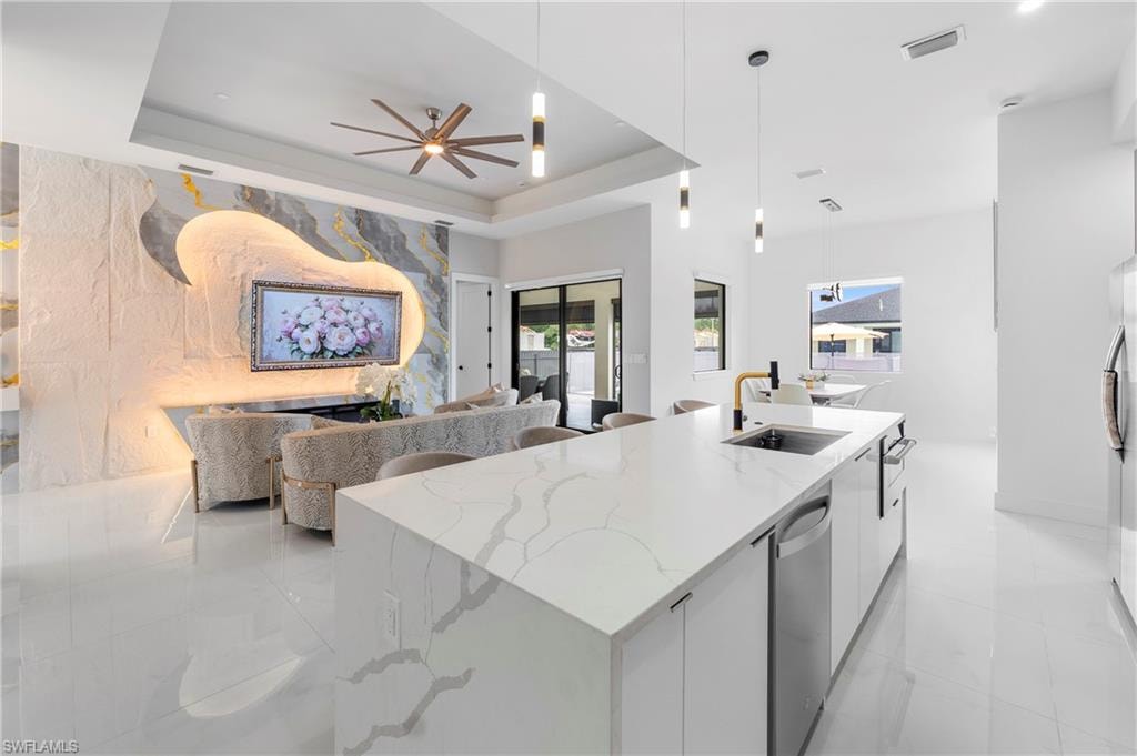 Spacious open-concept living area featuring an oversized kitchen island with an undermount sink and a gold-tone faucet