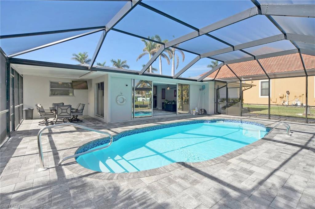 Swimming pool with a sunroom, a patio, and glass enclosure